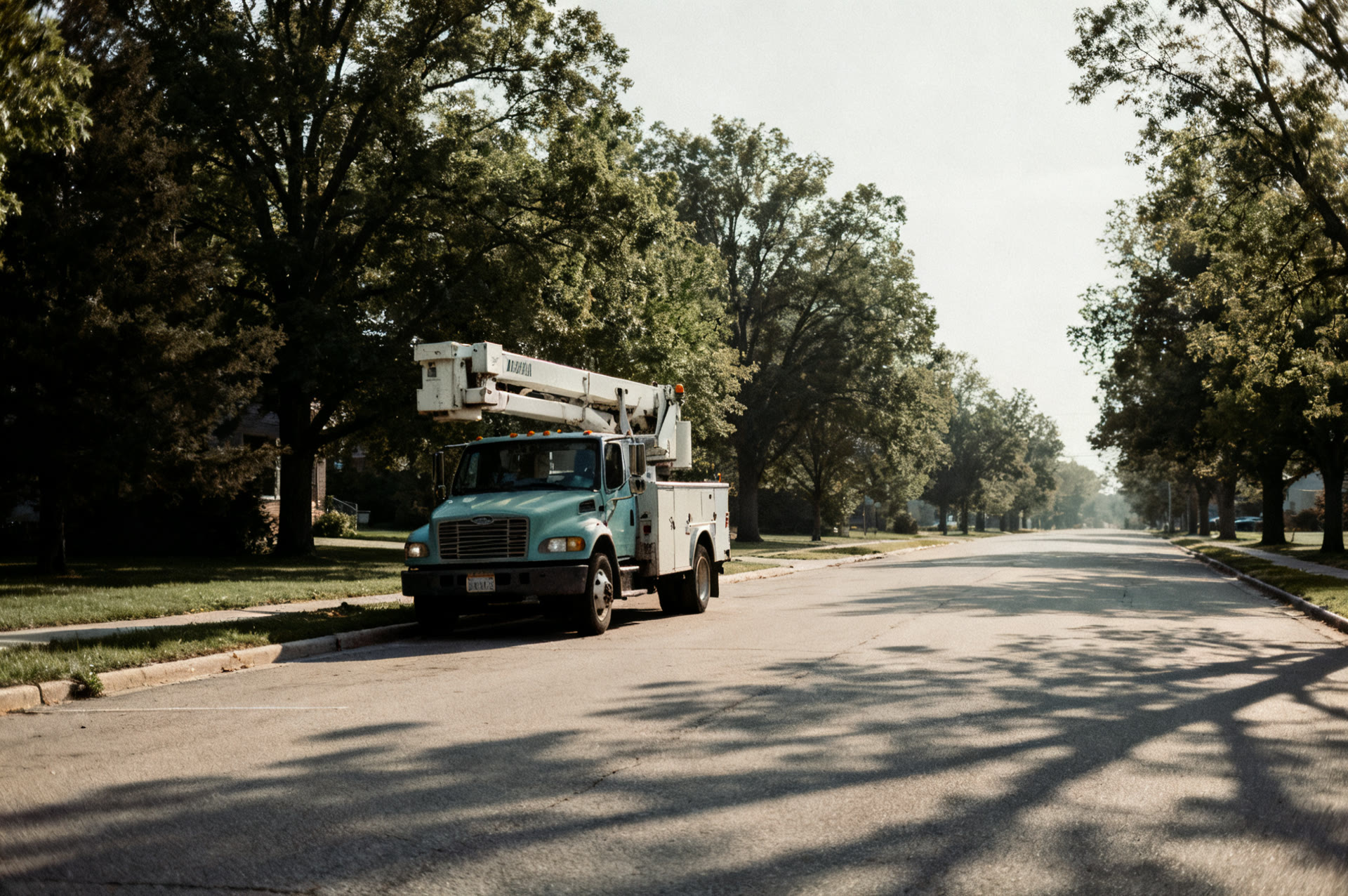 Bucket truck parked on a tree lined Delafield street in the morning